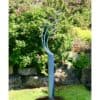 Modern silver garden sculpture with bird figures in colourful floral garden setting.