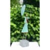 Bronze sculpture of a woman holding an umbrella, located outdoors with lush green foliage background.