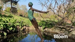 Vibrant garden sculpture of a woman reaching out, surrounded by lush greenery and water features at The Kildare Gallery.