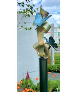 Shimmering metal sculpture with butterfly motifs at The Kildare Gallery, surrounded by colourful garden blooms.