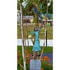 Vibrant outdoor sculpture of a woman in a dress, surrounded by trees and colourful garden artwork.
