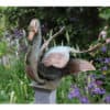Bronze heron sculpture in the garden of The Kildare Gallery, surrounded by colourful flowers and lush greenery.