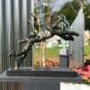 Intricate metal sculpture of a dog jumping, displayed outdoors at The Kildare Gallery.