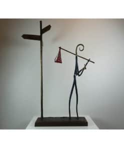 Modern artistic sculpture featuring a stylised figure holding a pole with hanging accessories, displayed at The Kildare Gallery.