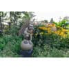 Astonishing stone gargoyle sculpture with detailed wings amidst colourful garden flowers.