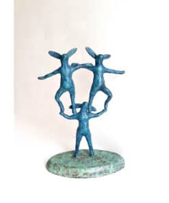 Blue rabbit sculpture with three figures connected in a circle, displayed on a textured round base.
