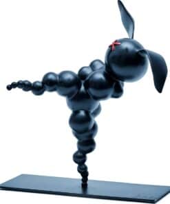 Playful black dog sculpture made of spheres with floppy ears and a red bow, displayed on a rectangular base.