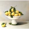 Bright yellow lemons with green leaves in a classic white pedestal bowl, a still life art piece at The Kildare Gallery.