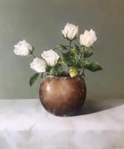 Soft white roses in a rustic bronze vase, displayed on a white table, capturing still-life art at The Kildare Gallery.