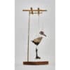 Intricate sculpture of a bird and skull hanging on a modern metal and wooden display stand.