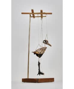 Intricate sculpture of a bird and skull hanging on a modern metal and wooden display stand.