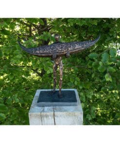 Modern metal sculpture of a figure with a boat on its head, set against lush green foliage, displayed at The Kildare Gallery.