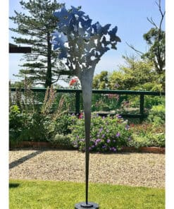 Decorative butterfly garden sculpture on a metal pole in vibrant garden setting at The Kildare Gallery.
