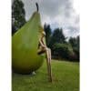 Pear-shaped sculpture with a sitting metallic figure in a lush garden setting, part of outdoor art display at The Kildare Gallery.