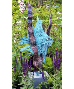Vivid blue chameleon sculpture placed among lush green foliage and purple flowers at The Kildare Gallery.