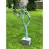 Bright blue metal sculpture of a stylised tree with small bird figures, outdoor garden installation.