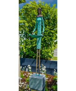 Elegant bronze sculpture of a woman holding a tray, set outdoors among lush green foliage at The Kildare Gallery.