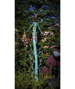 Colorful metal sculpture resembling a tree with antlers in a garden setting.