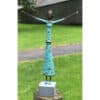 Handmade metal sculpture of a joyful woman with arms raised, outdoor garden setting.