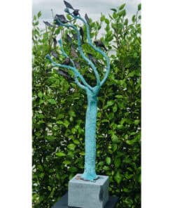 Bright blue artistic metal tree sculpture with black birds, set against lush green foliage, at The Kildare Gallery.