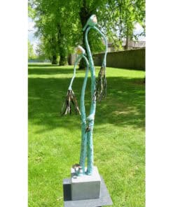 Whimsical garden sculpture inspired by nature with tall, slender figures and driftwood accents, displayed outdoors with lush greenery.