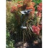 Metal bird sculpture in a colourful garden setting with red flowering plants.