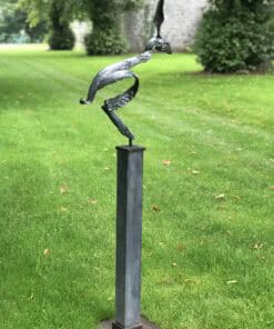 Sculpture of a heron in the Kildare Gallery garden, outdoor art piece on a grassy lawn surrounded by trees.