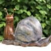 Colourful ceramic snail sculpture with a marble-like shell against a green leafy background.