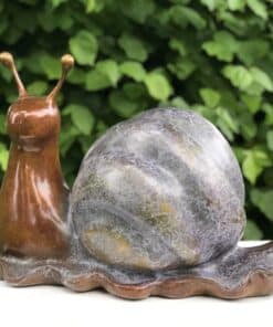 Colourful ceramic snail sculpture with a marble-like shell against a green leafy background.