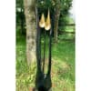 Elegant metal outdoor sculpture with black and gold accents, located in a lush garden setting.