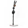 Intricate abstract sculpture of a rabbit in black metal with orange nose, displayed on a white pedestal.