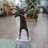 Elegant bronze sculpture of a deer aiming a bow, set on a stone base, displayed outside The Kildare Gallery.