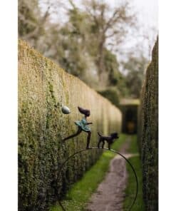 Whimsical sculpture of a girl and dog along the moss-covered garden wall at The Kildare Gallery.