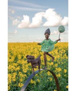Child sculpture in a green dress holding a balloon in a yellow flower field at The Kildare Gallery.
