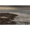 Dark coastal landscape photography with rocky shoreline and turbulent waves.