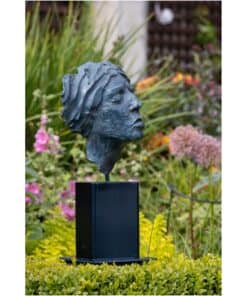 Modern bronze sculpture of a woman's profile at The Kildare Gallery garden, surrounded by colourful blooms.