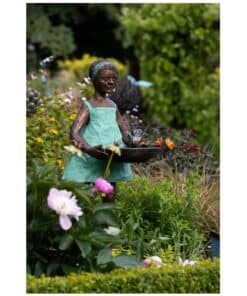 Handcrafted garden sculpture of a girl with flowers in a lush outdoor setting, showcasing contemporary Irish art.