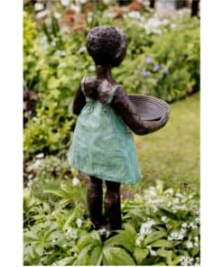Child sculpture holding a basket in a garden at The Kildare Gallery.