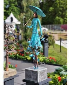 Bright blue metal sculpture of a woman holding an umbrella at The Kildare Gallery outdoor display.