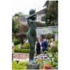 Bronze sculpture of a woman in an outdoor art garden, with visitors and lush greenery in the background.