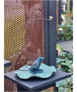 Elegant garden sculpture featuring a blue fox sitting on a leaf-shaped base. Carefully crafted art piece displayed outdoors.