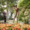 Bronze figure sculpture of a girl with outstretched arms amidst colourful flowers at The Kildare Gallery.