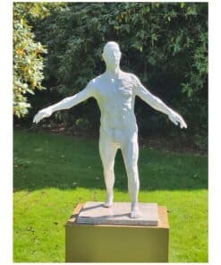 Modern sculpture of a male figure with outstretched arms, displayed outdoors in a garden setting.