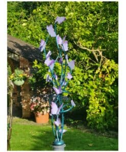 Blue floral sculpture with purple butterflies in a garden setting.