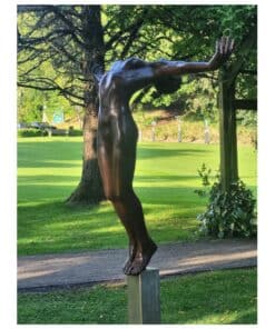 Bronze sculpture of a human figure with arms outstretched outdoors at The Kildare Gallery, surrounded by trees and greenery in a scenic garden setting.
