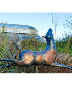 Modern bronze sculpture of a playful animal at The Kildare Gallery gardens, surrounded by lush greenery.