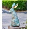 Blown-up image: a rabbit sculpture with large ears, abstract design, outdoors, on a wooden stand, greenery background, artistic modern sculpture, public art piece, Kildare Gallery.